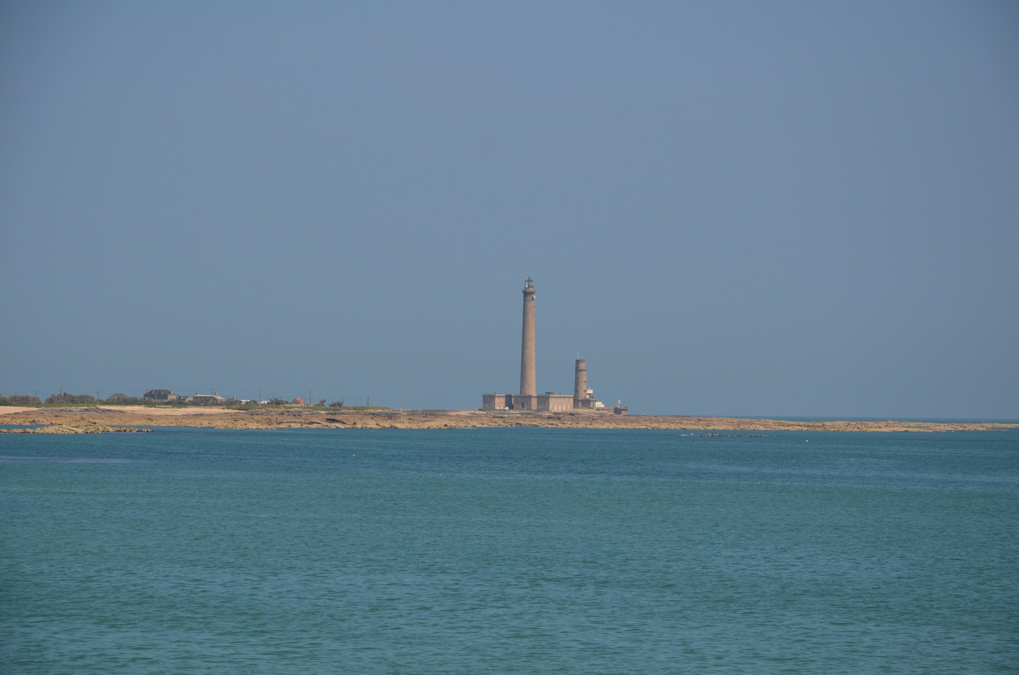 La pointe de Barfleur et le phare de Gatteville au loin, mer verte et ciel pâle de la Manche en juin