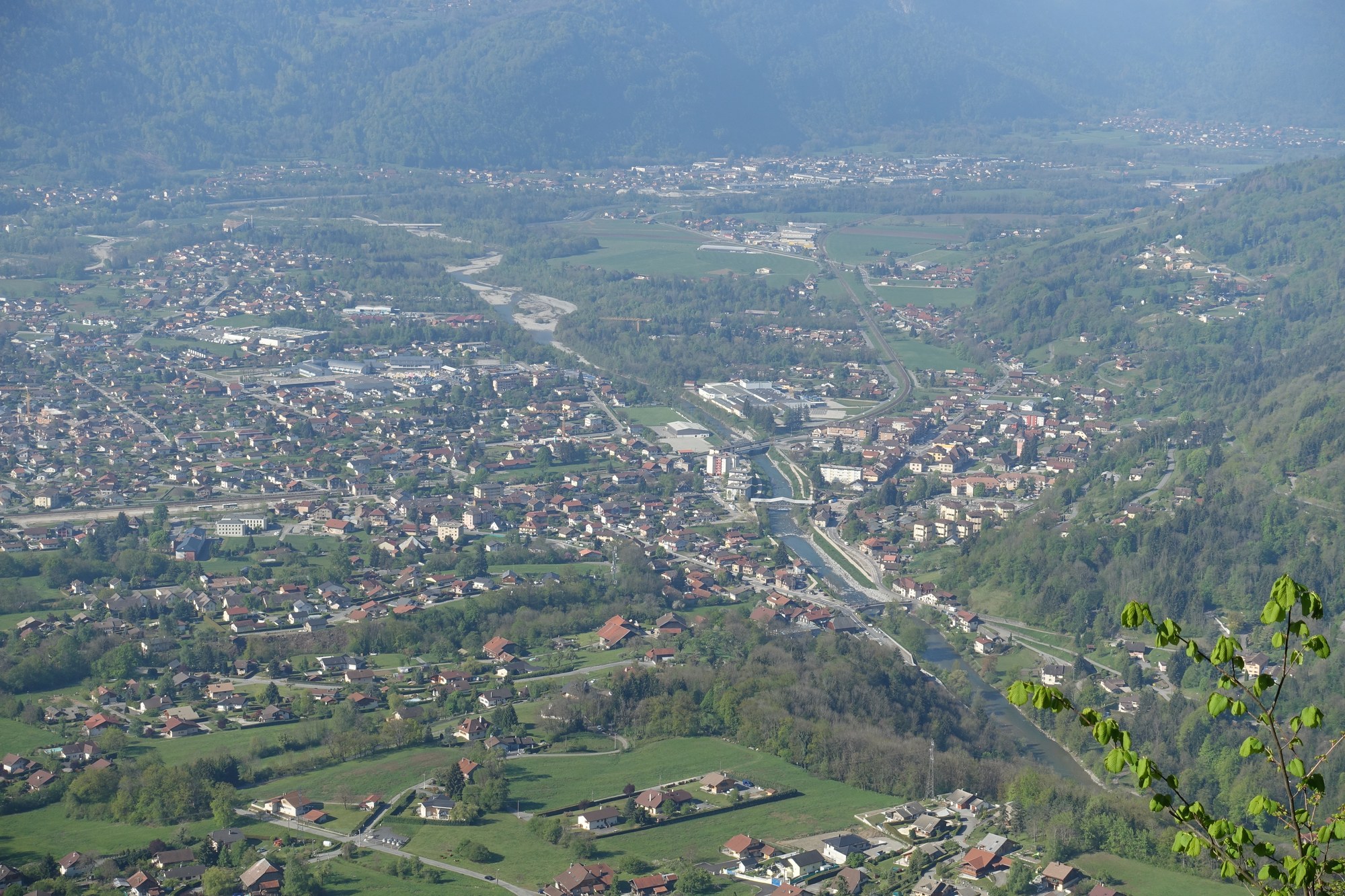 Vue plongeante sur le fond de la vallée de l'Arve à Marignier : la ville et ses prés serrés entre deux versants boisés, la rivière au milieu