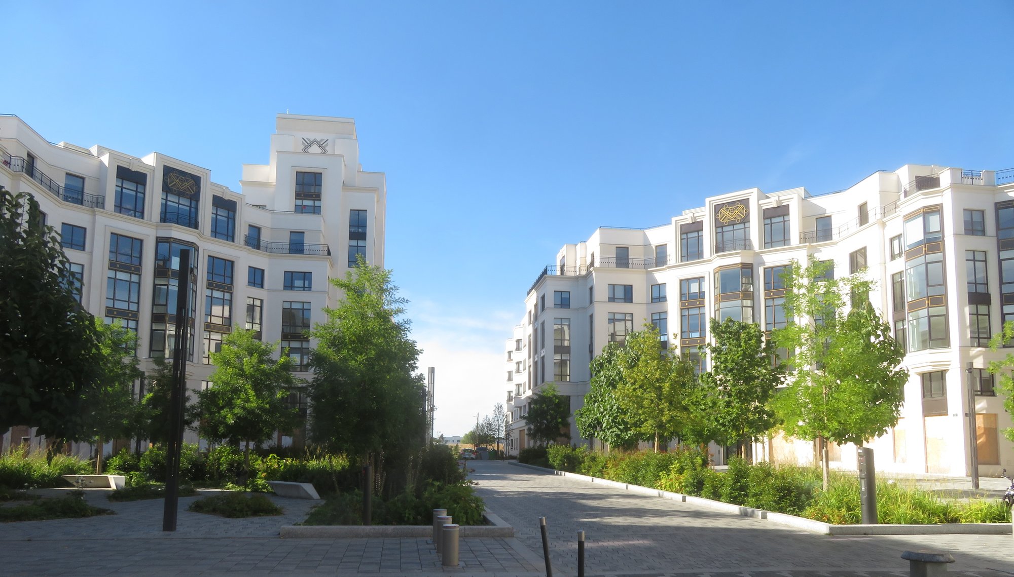 Deux immeubles de logements récents à Serris, de part et d'autre d'un mail piéton planté de jeunes arbres